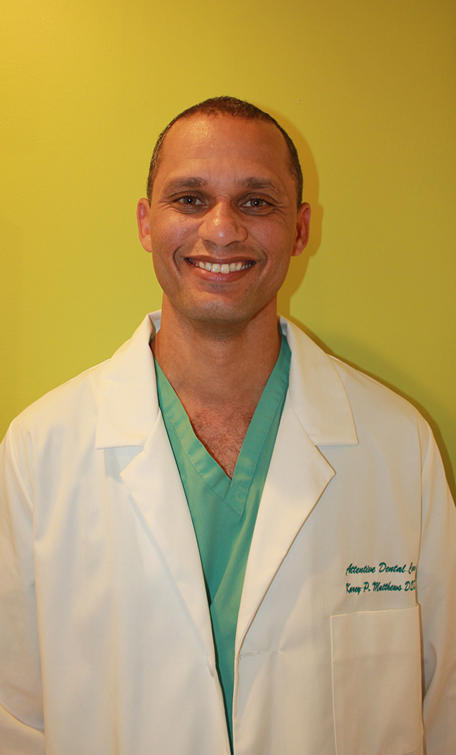 The image shows a man wearing scrubs and a stethoscope, standing in front of a yellow wall with a smile on his face.