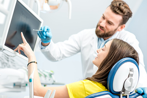 A dental professional assisting a patient with computer technology during a dental appointment.