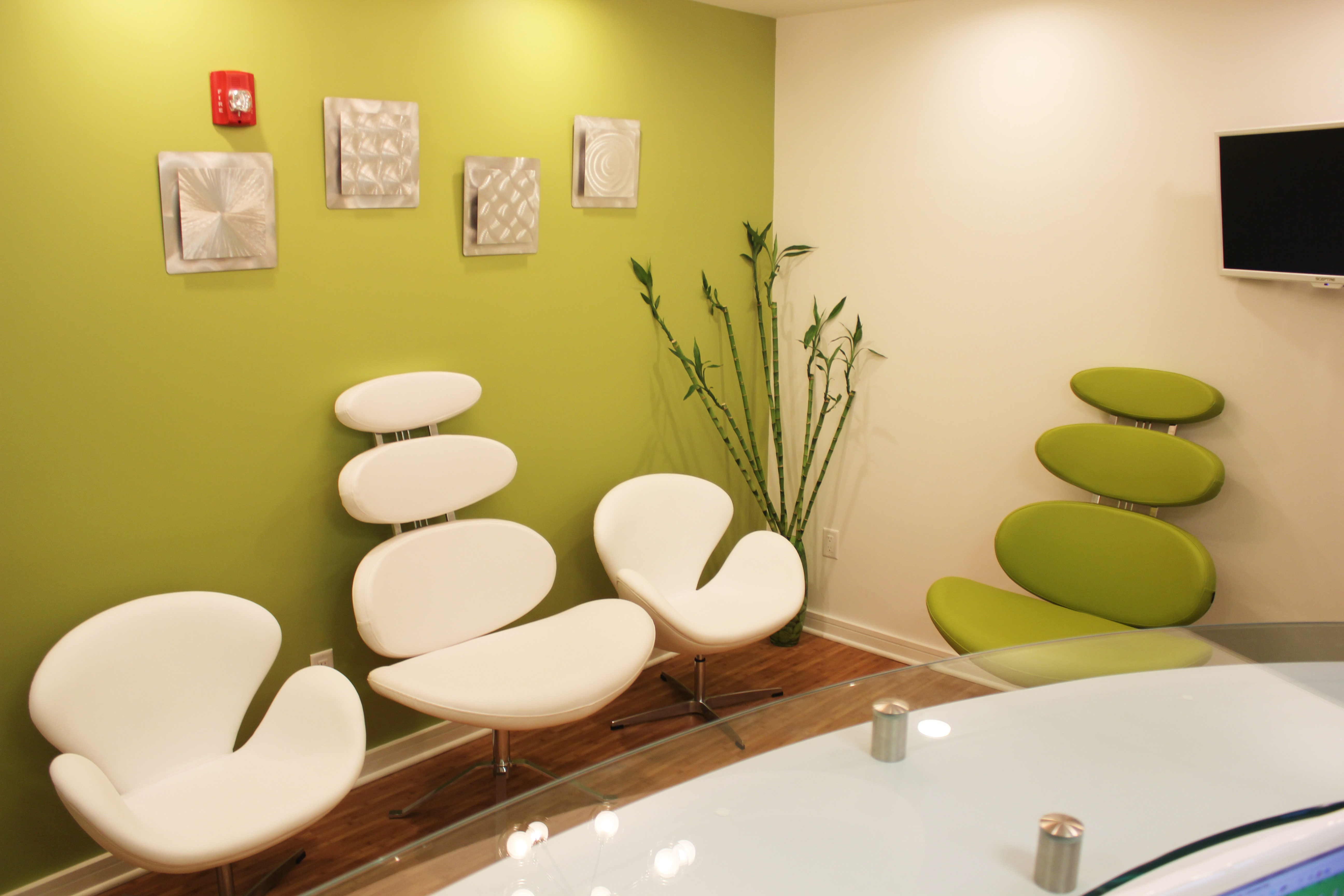 The image depicts a modern office space with contemporary furniture, including white chairs and a curved sofa, arranged around a central area.