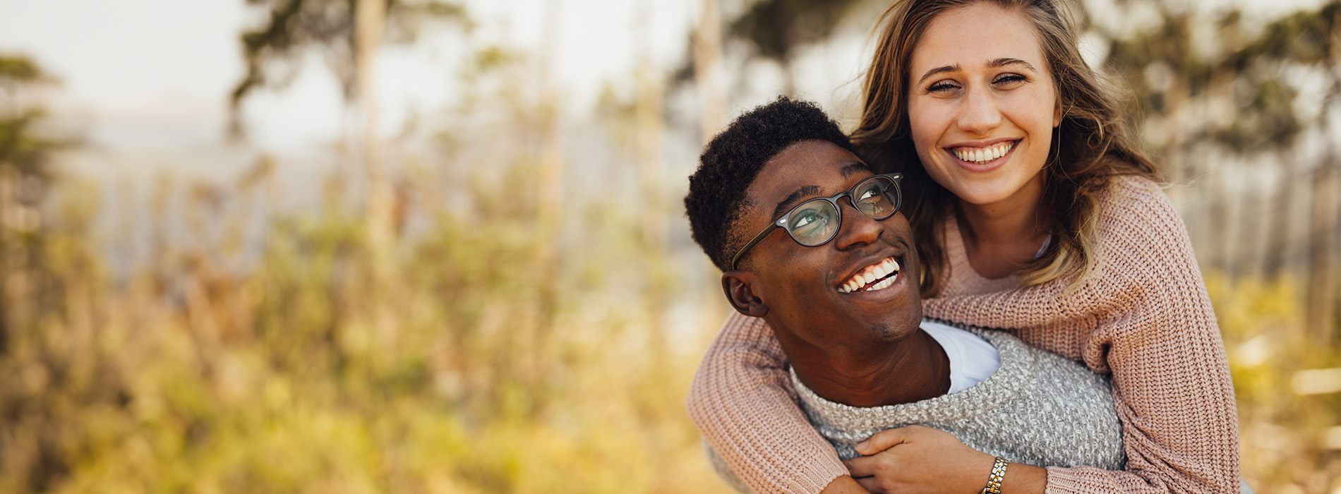 A young man and woman are embracing each other outdoors during daylight hours.